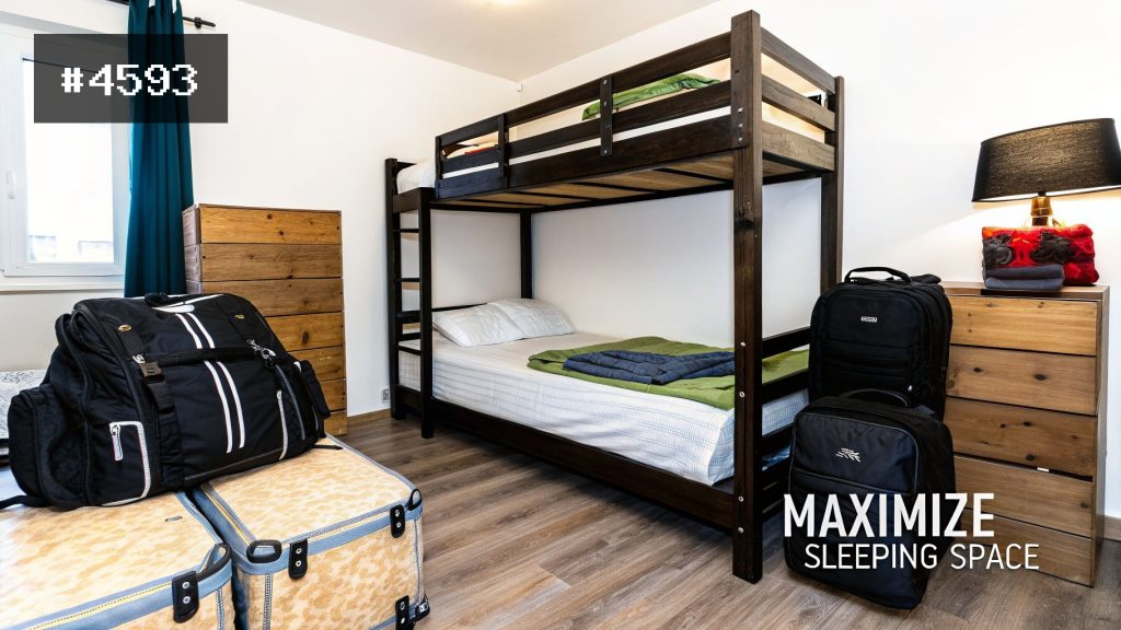 A cozy bedroom featuring a solid wood bunk bed, with two beds, luggage, and wooden storage, optimizing sleeping space.